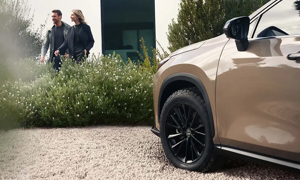 Zbliżenie na koło Lexusa NX z dwiema osobami w tle